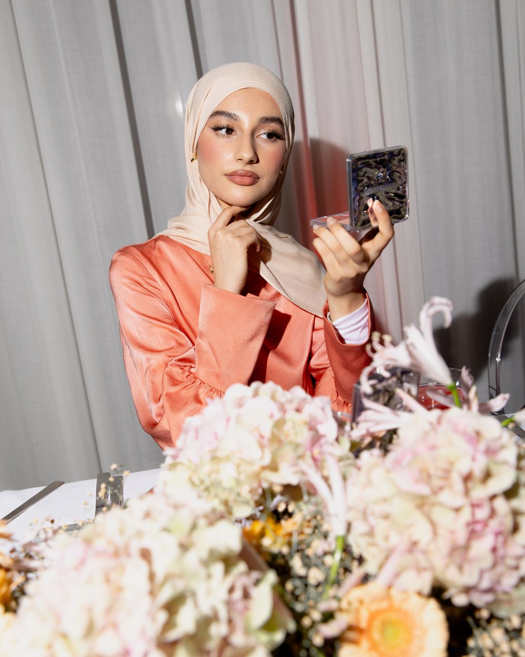 Gast tijdens het Huda Beauty Blush Filter launch dinner event met Huda Beauty branding op de achtergrond.